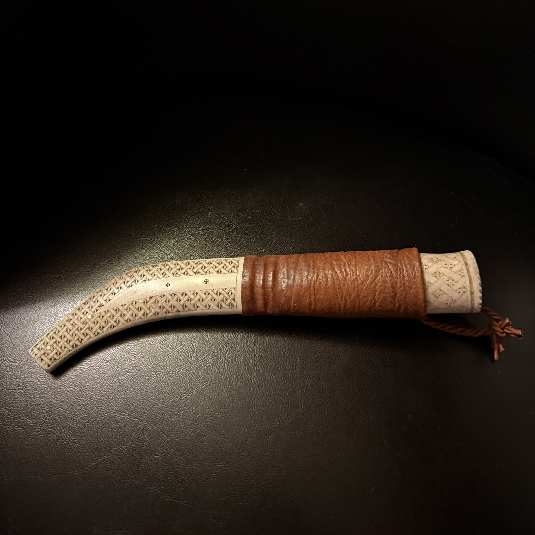 Halvhornskniv med sydsamisk form och gravyr i design av Same/Duodjislöjdare Sven-Åke Risfjell från Vilhelmina i Södra Lappland. Knivens hela längd är 26 cm. Knivskaftet är i renhorn och även det med sydsamisk gravyr. Bladet i damasksmide är tillverkat av Mikael Styrefors. Bladets längd är 10 cm. Knivens upphängningsanordning är gjord i tvinnat renskinn. Risfjells Sameslöjd Vilhelmin