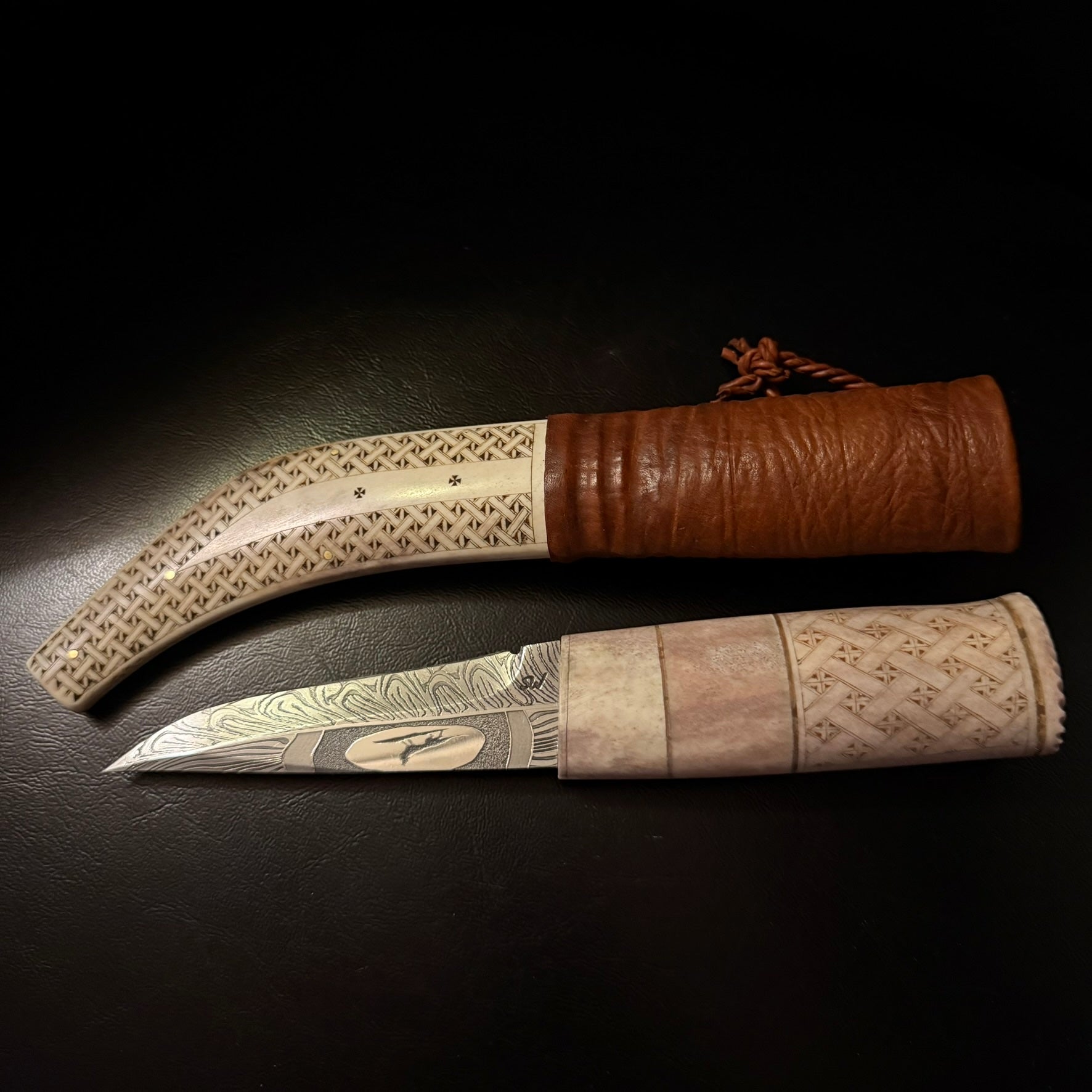 Halvhornskniv med sydsamisk form och gravyr i design av Same/Duodjislöjdare Sven-Åke Risfjell från Vilhelmina i Södra Lappland. Knivens hela längd är 26 cm. Knivskaftet är i renhorn och även det med sydsamisk gravyr. Bladet i damasksmide är tillverkat av Mikael Styrefors. Bladets längd är 10 cm. Knivens upphängningsanordning är gjord i tvinnat renskinn. Risfjells Sameslöjd Vilhelmina