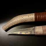 Halvhornskniv med sydsamisk form och gravyr i design av Same/Duodjislöjdare Sven-Åke Risfjell från Vilhelmina i Södra Lappland. Knivens hela längd är 26 cm. Knivskaftet är i renhorn och även det med sydsamisk gravyr. Bladet i damasksmide är tillverkat av Mikael Styrefors. Bladets längd är 10 cm. Knivens upphängningsanordning är gjord i tvinnat renskinn. Risfjells Sameslöjd Vilhelmin