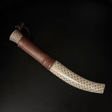 Halvhornskniv med sydsamisk form och gravyr i design av Same/Duodjislöjdare Sven-Åke Risfjell från Vilhelmina i Södra Lappland. Knivens hela längd är 25 cm. Knivskaftet är i renhorn och även det med sydsamisk gravyr. Bladet i kolstål tillverkad av Sven-Åke. Bladets längd är 9,5 cm. Knivens upphängningsanordning är gjord i tvinnat renskinn.