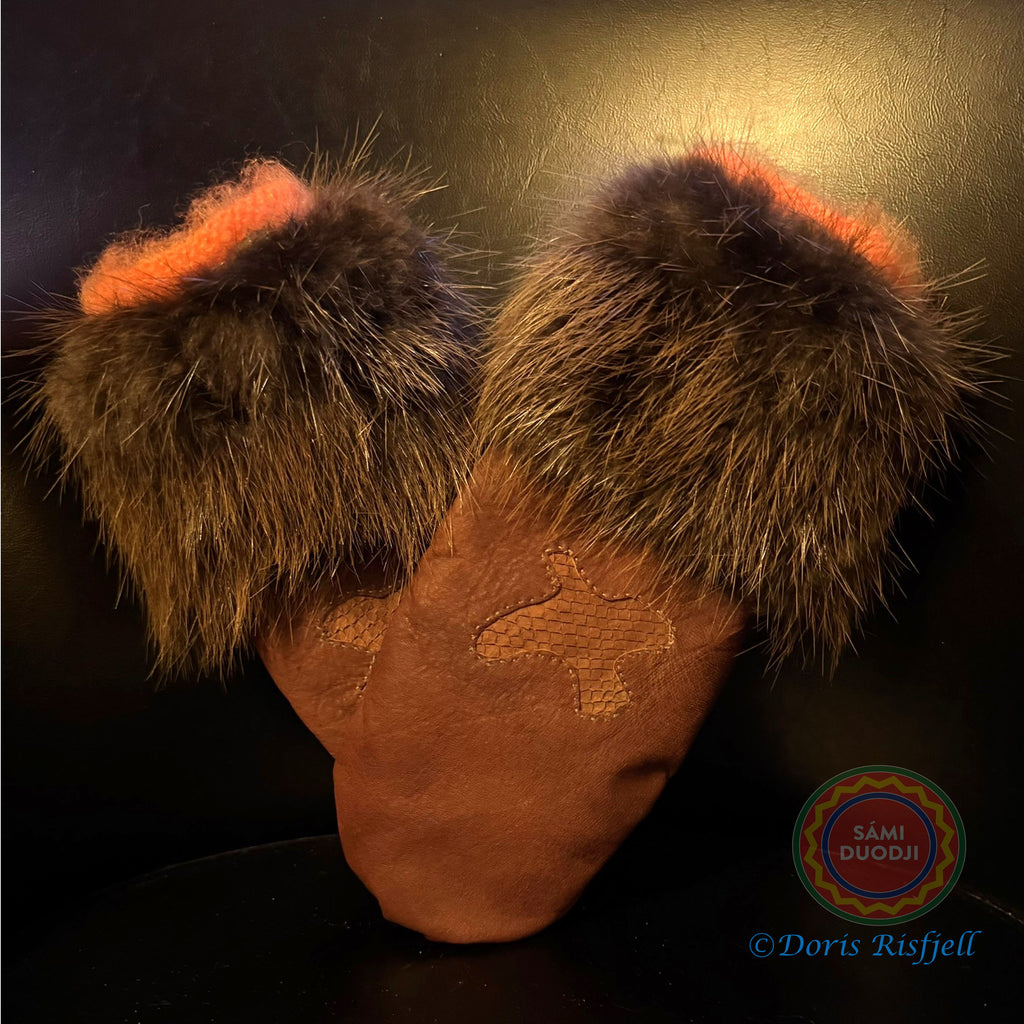 Renskinnshandskar med bräm av bäverskinn av sameslöjdare Doris Risfjell, Risfjells Sameslöjd Vilhelmina. Handskarna har en dekoration av en ripa i laxskinn. Innervanten som är stickad i mohair gör handskarna extra varma, mjuka och sköna. Här i orange garn. Storlek 7-8 liten dam. Risfjells Sameslöjd i Vilhelmina.