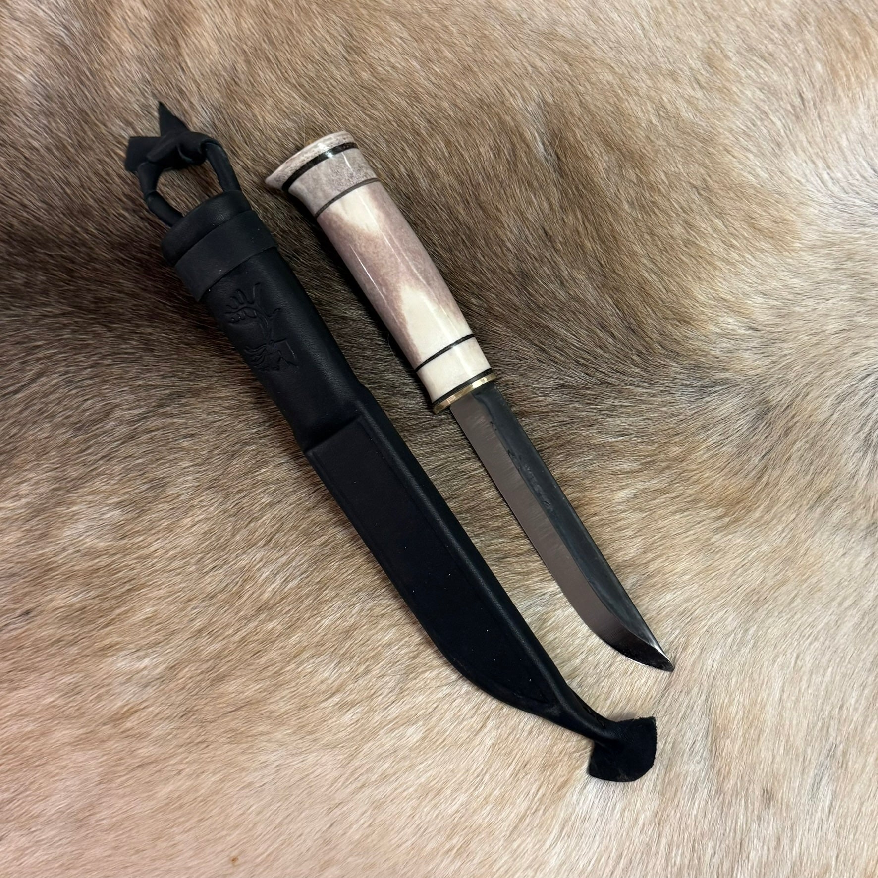Jakt och fiskekniv 125 mm med renhornskaft och smalt blad. Ej egen tillverkning men i vårt utbud i vår butik. Längd på kniven i höslter 28 cm där knivens blad mäter 125 mm. Svart läderslida medföljer. Risfjells Sameslöjd i Vilhelmina.