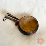 En kåsa ur björkvril med horninlägg i skaftet av same/Duodjislöjdare Sven-Åke Risfjell. Gravyren är av sydsamisk tradition. Kåsan rymmer 1,5-2 dl. Koppens diameter 9 cm. Kåsans längd är 15,5 cm och höjd 5 cm. Tvinnad rem av renskinn med tofs i kläde i rött och grönt. Risfjells Sameslöjd i Vilhelmina, södra Lappland