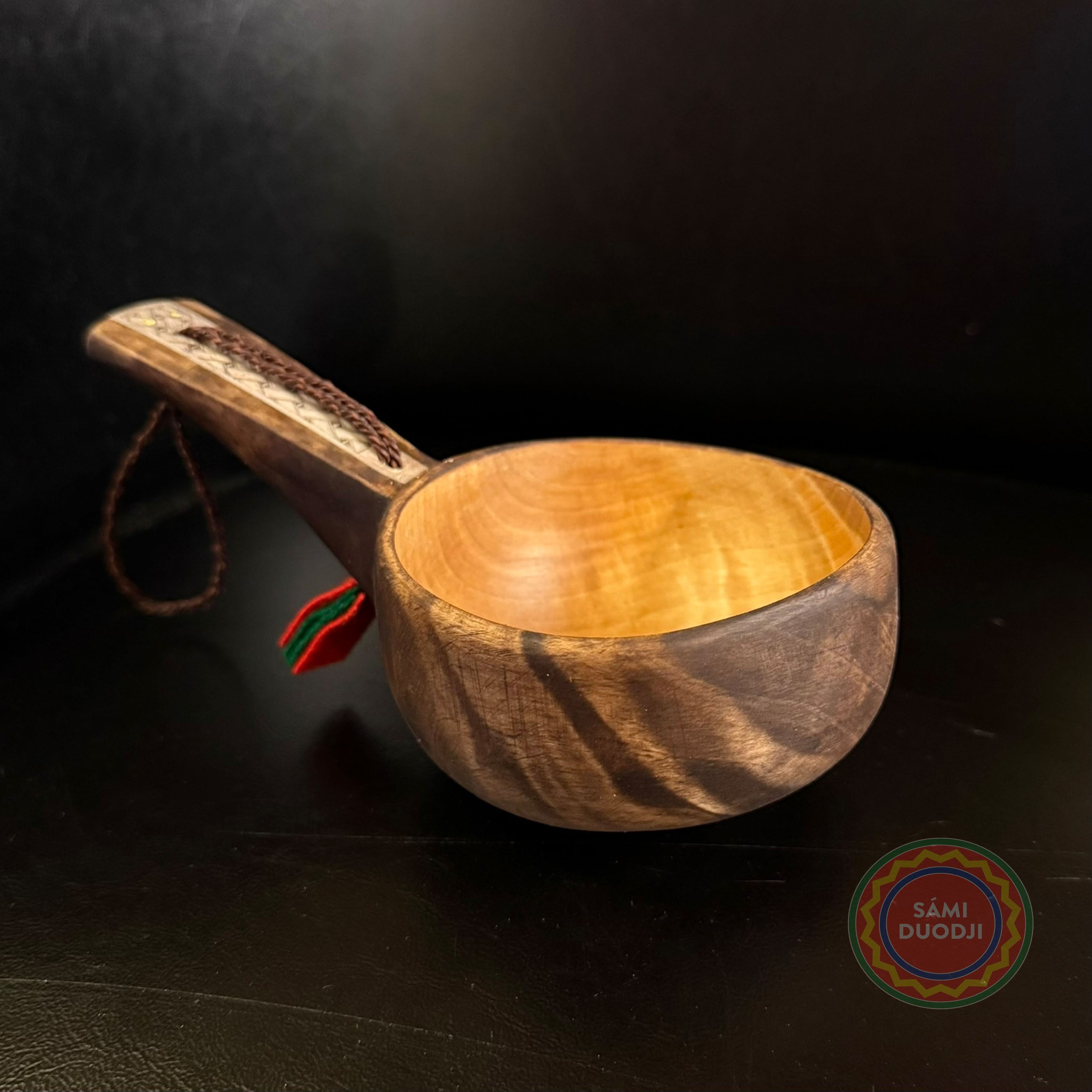 Kåsa ur björkvril med horninlägg och sydsamisk mönstergravyr av Duodji sameslöjdare Sven-Åke Risfjell Vilhelmina. Kåsans längd är 16cm och diameter 9,2 cm. Höjden på kåsan är 5,3 cm. Den rymmer 1,5-2 dl. Risfjells Sameslöjd i Vilhelmina södra Lappland.