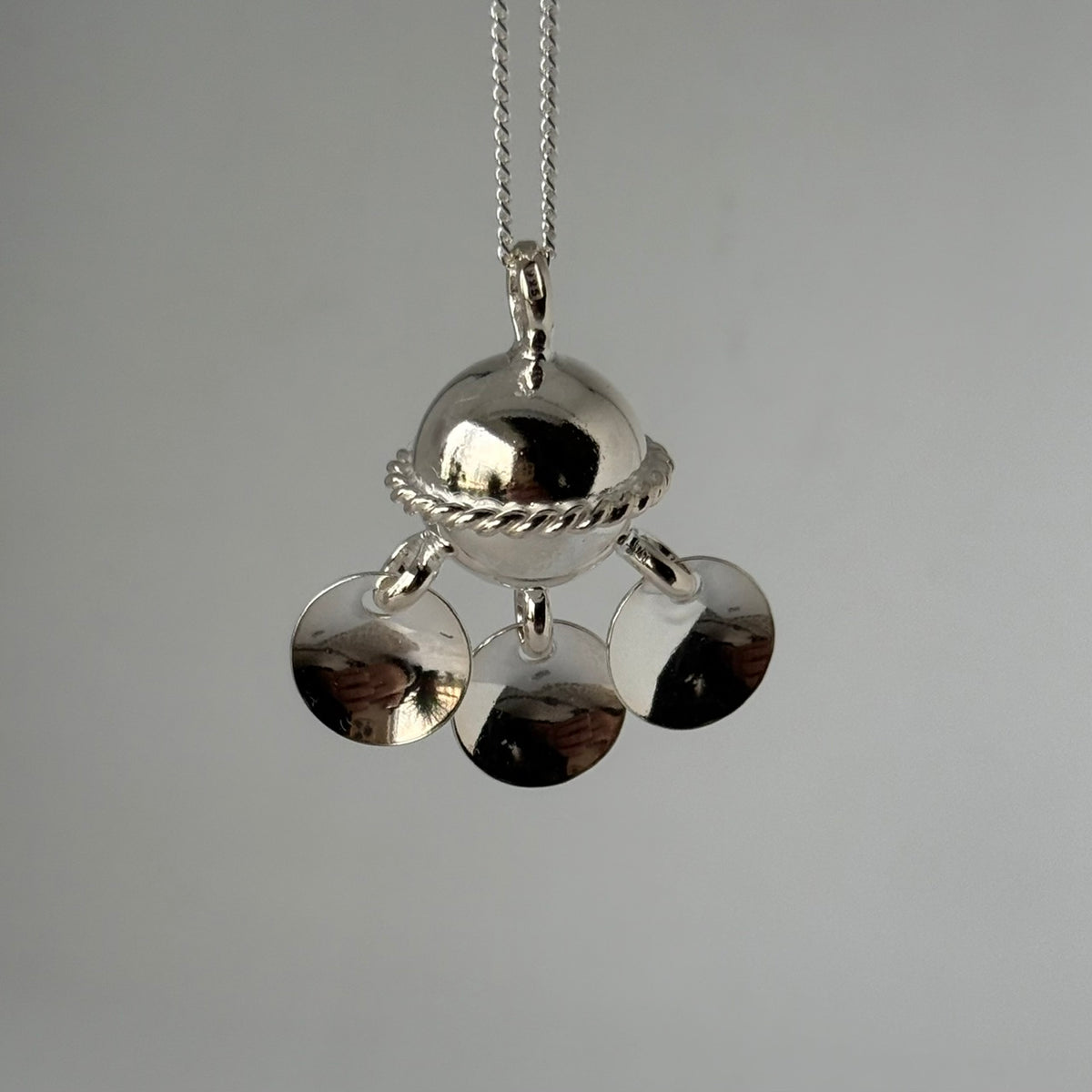 Halsband Komsekula i silver med tre tallrikshängen som hänger i kulans nedre del. Kulans diameter är 15 mm. Denhar en midja och med den blir diametern 20 mm. Lövens diameter är 12 mm. silverkedja 45 cm medföljer. Finns hos Risfjells Sameslöjd i Vilhelmina.