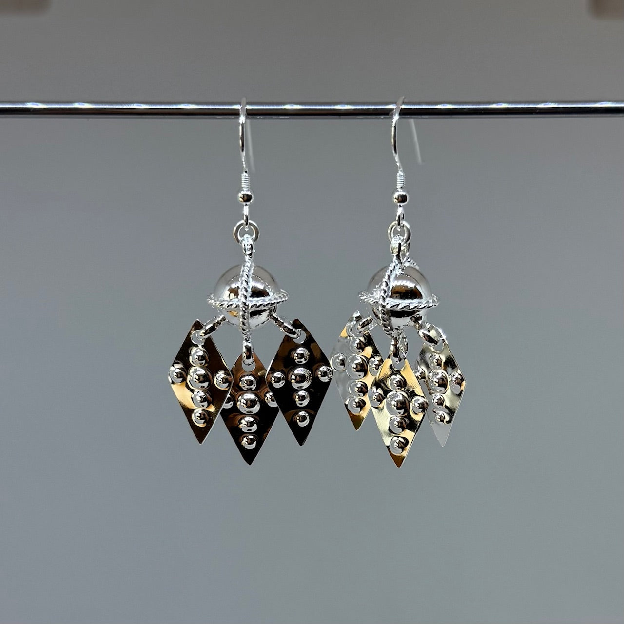 Örhängen i silver med vacker komsekula i silver med tre silverlöv i förlaga från Raukasjö, Jämtland. Kulans diameter är 10 mm med midja 12 mm. Längd 5 cm.Samiskt traditionssmycke. Finns hos Risfjells Sameslöjd i Vilhelmina södra Lappland.