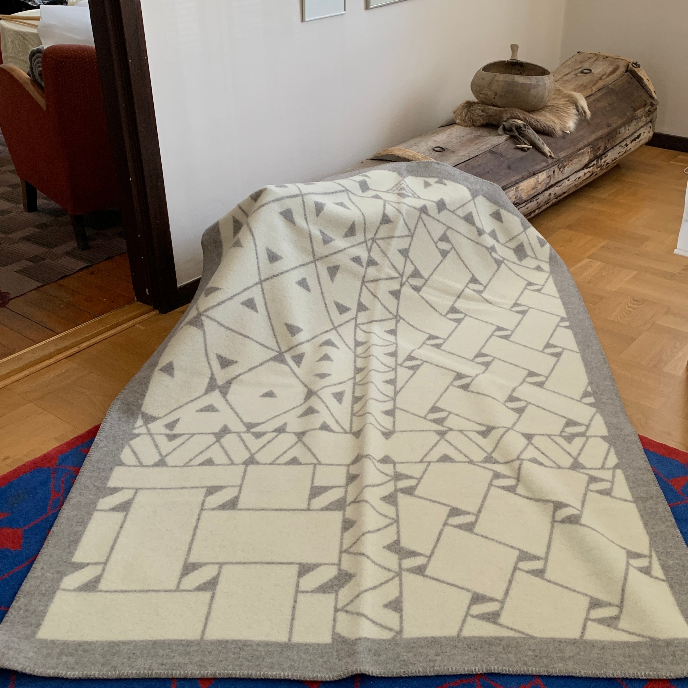 Pläd i ull. En unikt designad pläd av sameslöjdarna Doris och Sven-Åke Risfjell Vilhelmina Risfjells sameslöjd. Det gamla Nåjdmönstret från Marsfjäll återbördat i slöjden igen av Sven-Åke Risfjell och i textil produktion av Doris Risfjell. Här i gråvit färgställning.