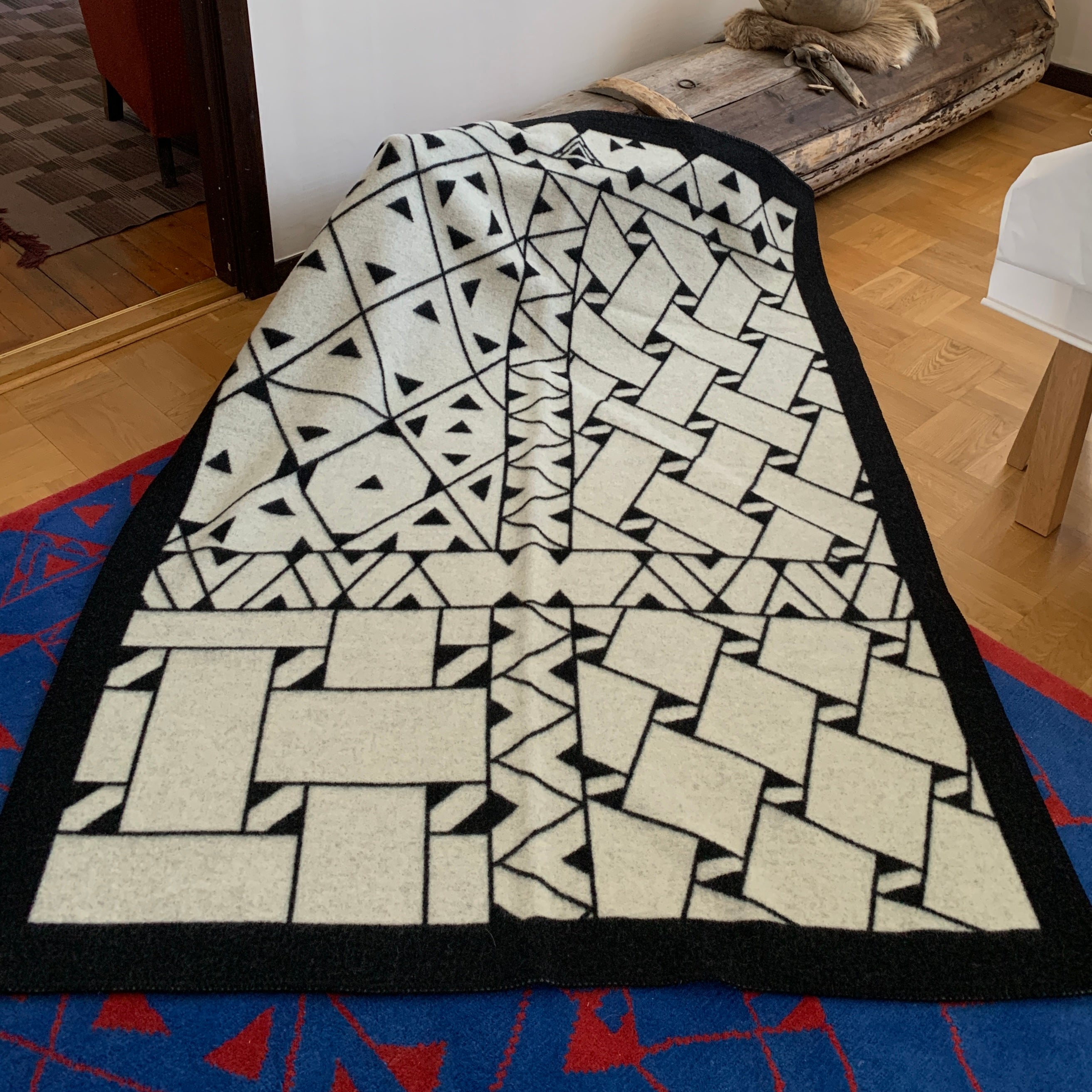 Pläd i ull. En unikt designad pläd av sameslöjdarna Doris och Sven-Åke Risfjell Vilhelmina Risfjells sameslöjd. Det gamla Nåjdmönstret från Marsfjäll återbördat i slöjden igen av Sven-Åke Risfjell och i textil produktion av Doris Risfjell. Här i svartvit färgställning.