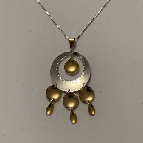 Samiskt smycke i silver och förgyllda hängen. Ring med gravyr och runt förgyllt hänge i mitten dessutom&nbsp; tre rader med förgyllda hängen som är runda och skedformade. Silverringens diameter 3,7 cm. &nbsp;Smyckets hela längd från fästets övre del ner till hängets nedersta löv är 6,5 cm. Silverkedja är 70 cm lång. LL design. Finns hos Risfjells Sameslöjd i Vilhelmina, södra Lappland.