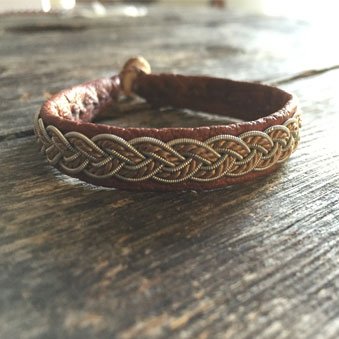 Tenntrådsarmband Inflätat gult garn på brunt skinn. Samiskt hantverk Doris Risfjell Vilhelmina Risfjells Sameslöjd