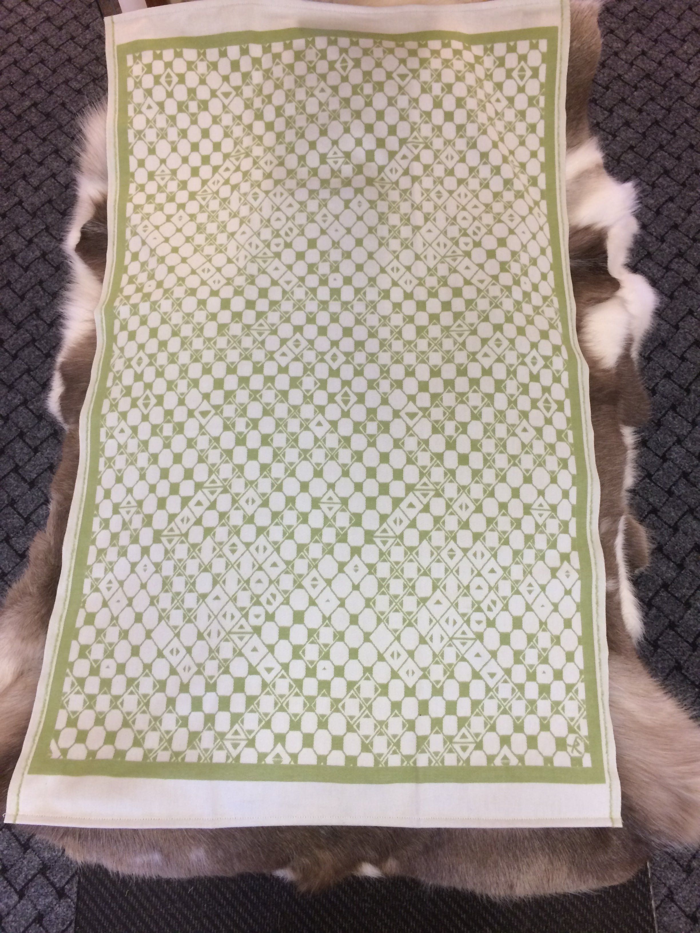 Barnfilt Marsfjällsnåjdens mönster i Doris och Sven-Åke Risfjells design,Risfjells Sameslöjd i Vilhelmina, södra Lappland. Filten i mjuk och skön bomullsflanell. Här är Nåjdmönstret i grön komposition från Marsfjällsnåjdens Daaskoe.