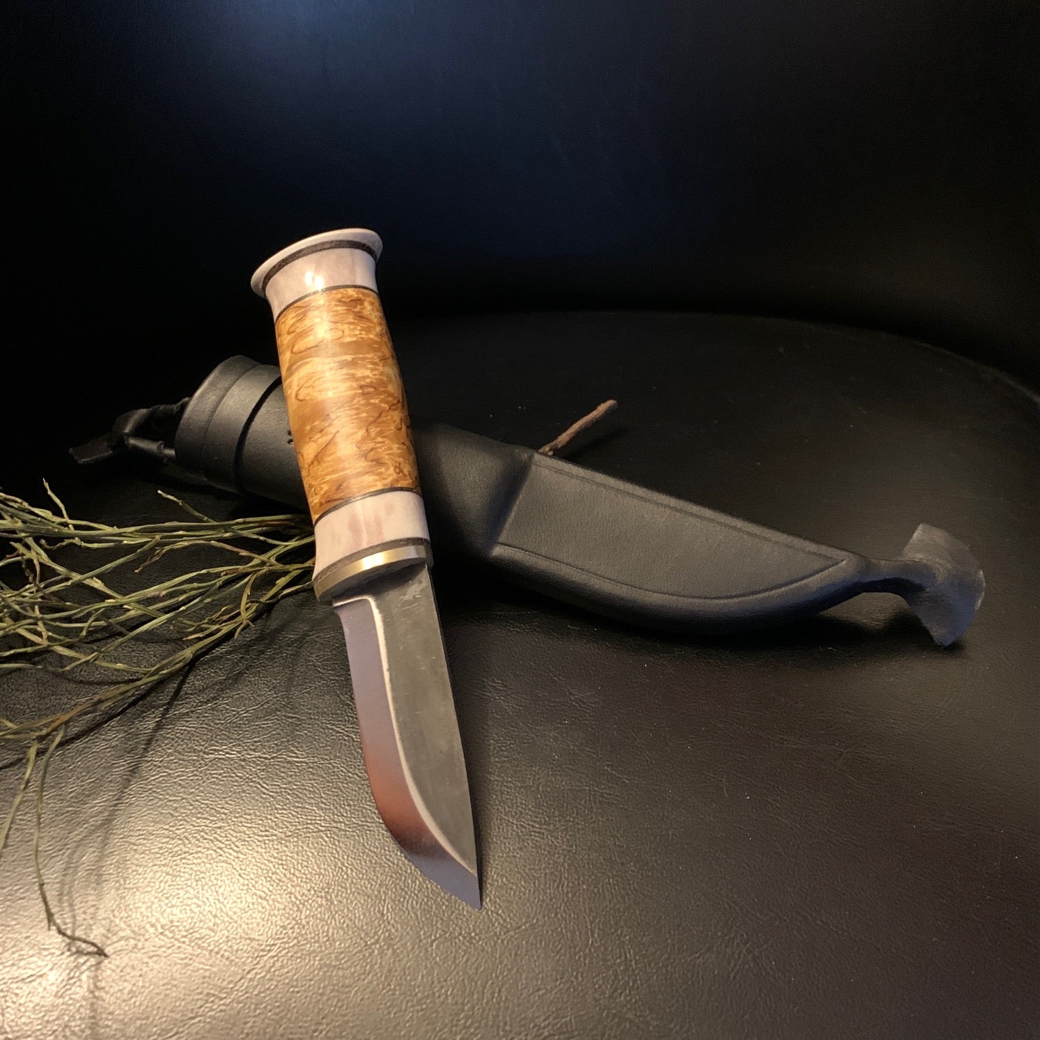 Jaktkniv i horn och björkmasur med brett kort blad i kolstål. Knivens hela längd i fodral är 24 cm. Knivbladet 80 mm långt och 24 mm brett. Finns hos Risfjells Sameslöjd i Vilhelmina