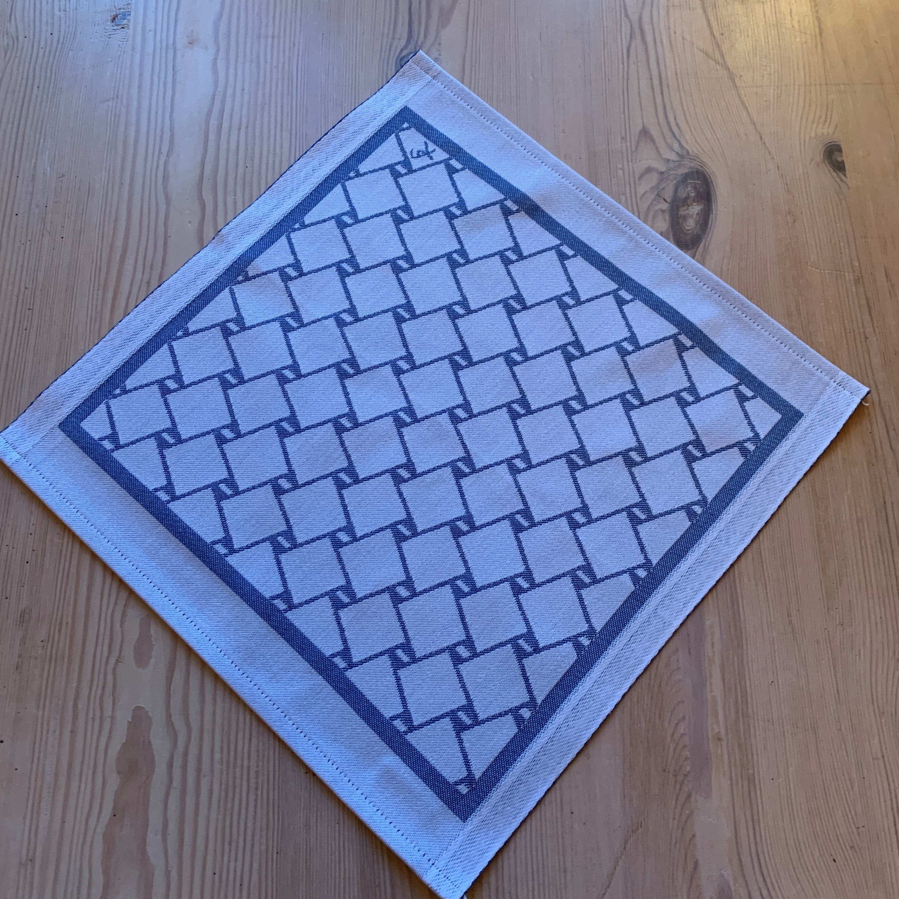 En bordstablett eller servett med nr tre av de tre sydsamiska flätmönster som går att återfinna på Marsfjällsnåjdens Daaskoe-väska som Sven-Åke Risfjell har satt ljus på i sin detaljstudie av väskan som han hittade tecknad i en bok i slutet av 1990-talet.  Här blå fläta på vit botten.