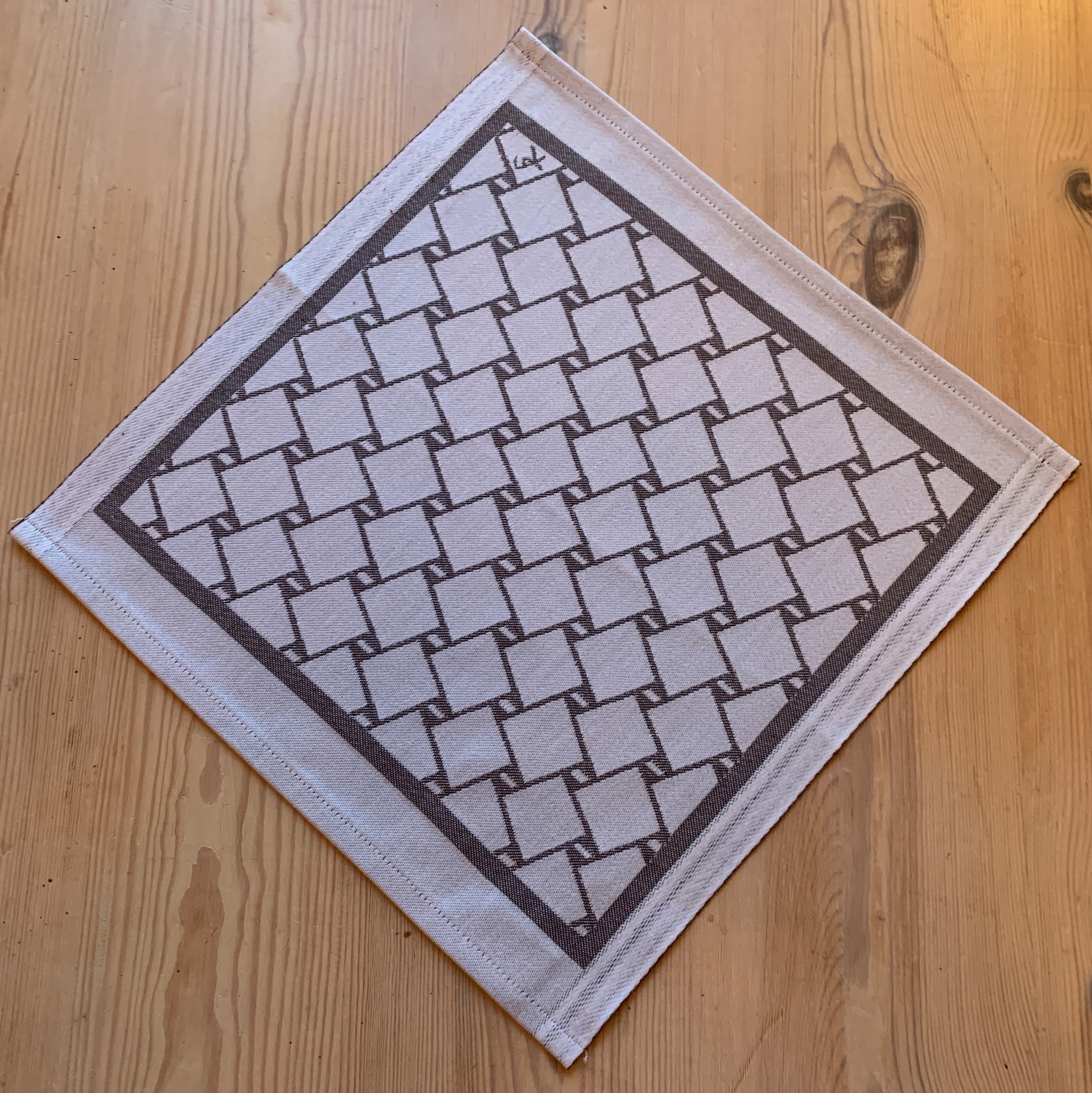 En bordstablett eller servett med nr tre av de tre sydsamiska flätmönster som går att återfinna på Marsfjällsnåjdens Daaskoe-väska som Sven-Åke Risfjell har satt ljus på i sin detaljstudie av väskan som han hittade tecknad i en bok i slutet av 1990-talet.  Här brun fläta på vit botten.