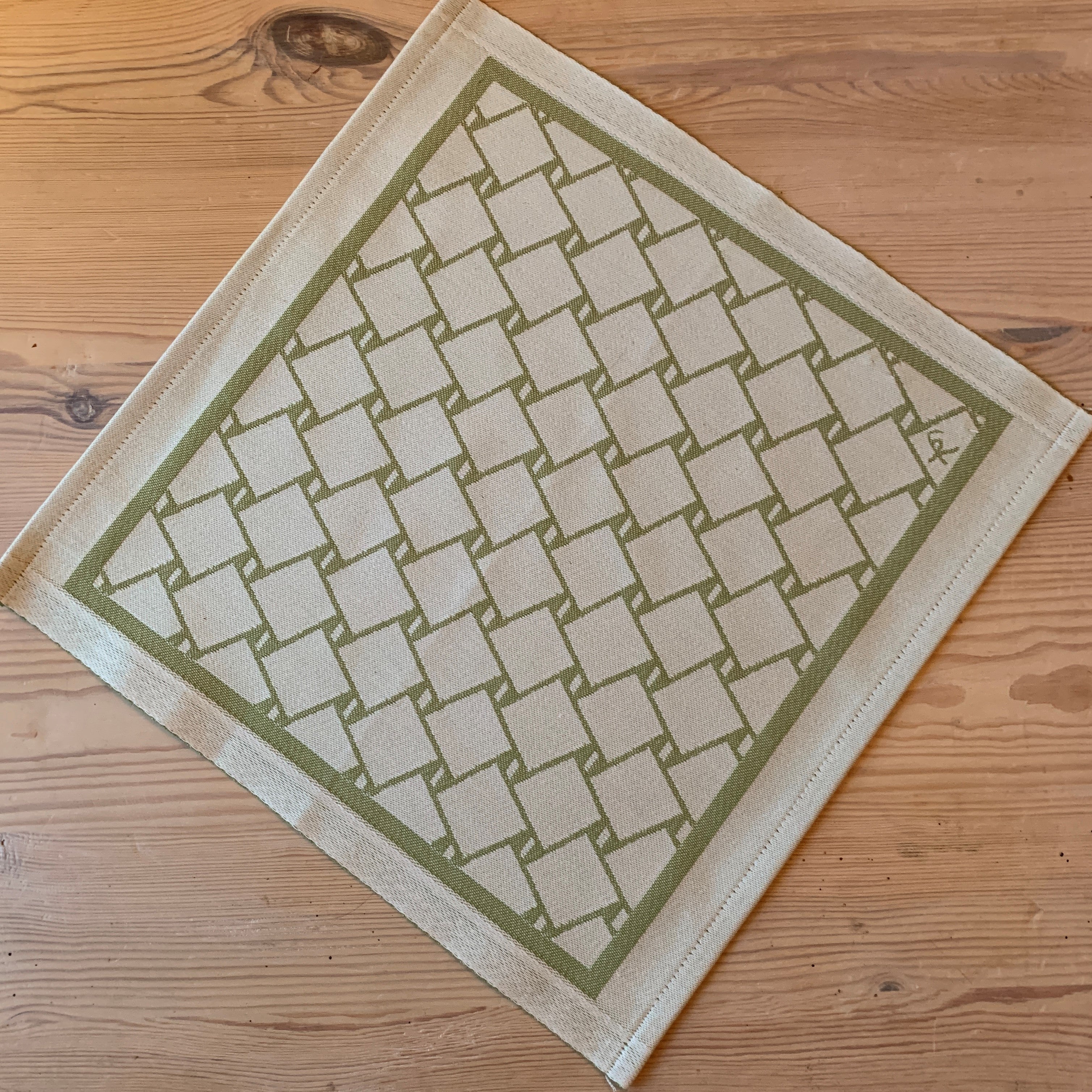 En bordstablett eller servett med nr tre av de tre sydsamiska flätmönster som går att återfinna på Marsfjällsnåjdens Daaskoe-väska som Sven-Åke Risfjell har satt ljus på i sin detaljstudie av väskan som han hittade tecknad i en bok i slutet av 1990-talet.  Här grön fläta på vit botten.