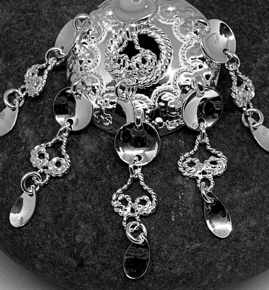 Samiskt silverbrosch med rik utsmyckning. Runda och skedformade löv på sex hängen. Diameter på bucklan som är punsad och dekorerad med filigranarbete är 30 mm. Hängena är 32 mm långa.  Broschet är en kopia på Sven-Åke Risfjells farmor Sara Alvina Sofia Sjulsdotters brosch. Broschet är fotat på Sara Avinas kaffesten med vilken hon malde sina kaffebönor. finns hos Risjfells Sameslöjd i Vilhelmina.