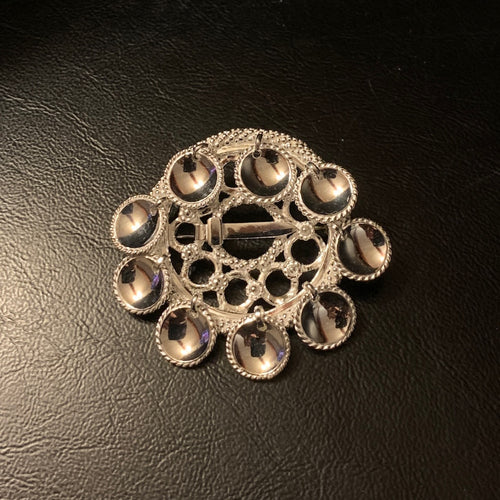 Brosch Riskuu i silver nio runda löv. Filigranarbete runt löven och hela broschets runda ring. Diameter på ringen är 4 cm. Höjd med löv är 5 cm. Finns hos Risjfells Sameslöjd i Vilhelmina, södra Lappland.