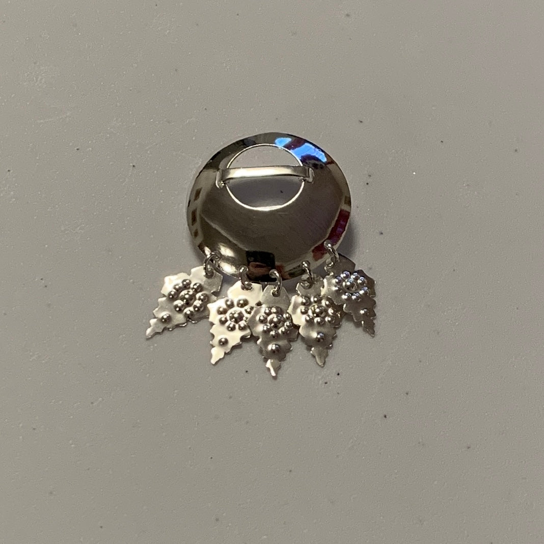 Brosch samisk i silver buckla med fyra punsade löv. Diameter 34 mm. Broschets höjd med löv är 55 mm. Finns hos Risfjells Sameslöjd i Vilhemina, södra Lappland