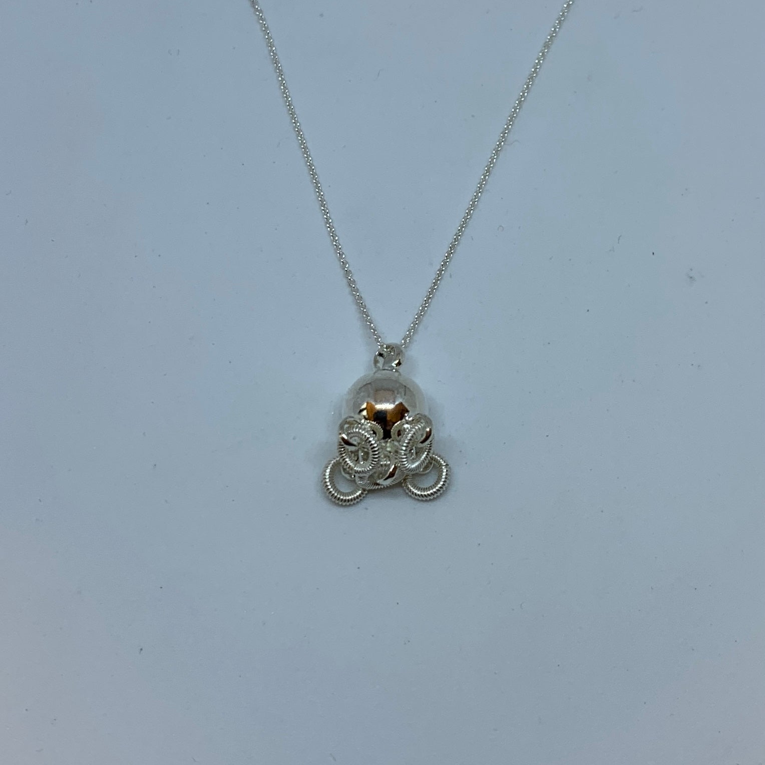 Komsekula i silver med fem små ringar. Diameter 10 mm. Silverkedja i silver 45 cm. Komsekulan är ett samiskt kultursmycke. Finns hos Risjfells Sameslöjd, Vilhelmina i södra Lappland