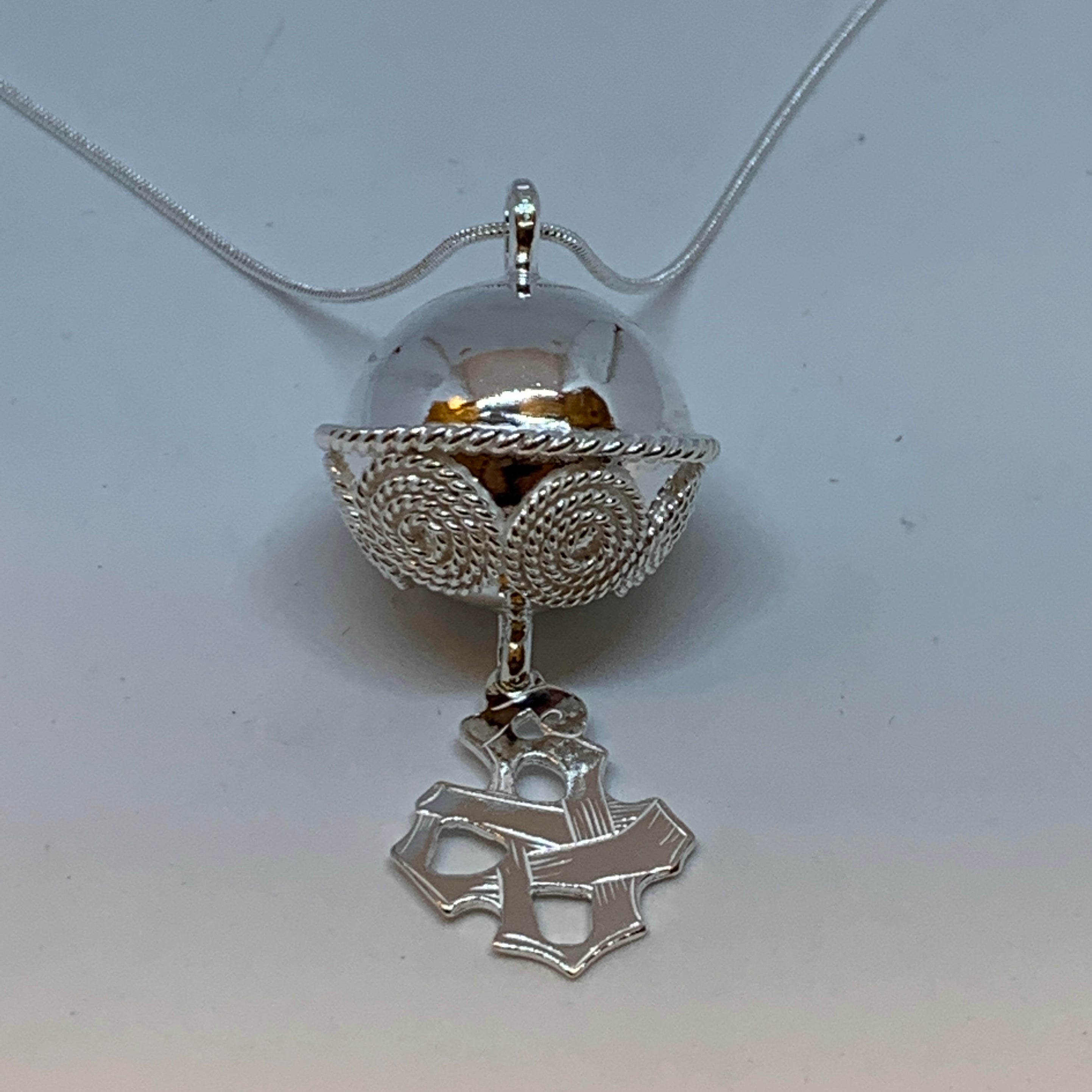 Halsband i silver Komsekula 25 mm i diameter. Kulan har en midja och har ett vackert filigranarbete på nedre halvan. Hänget Gotiska knuten är 25 mm hög och 20 mm bred. Kulans och hängets hela längd mäter 60 mm. Dilverkedjan är 60 cm lång. Komsekulan är ett samiskt kultursmycke. Finns hos Risfjells Sameslöjd i Vilhelmina.