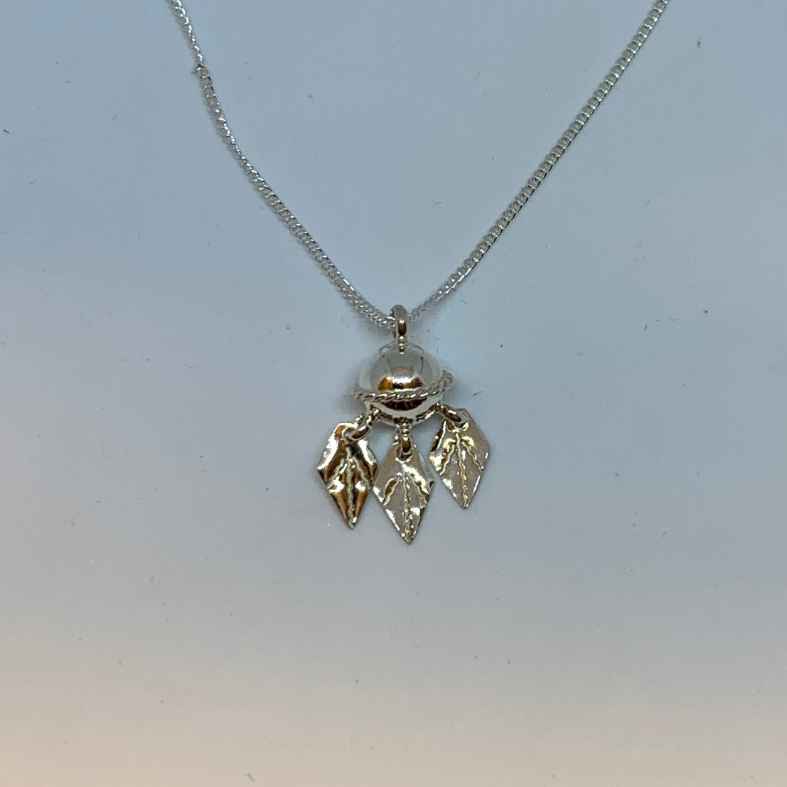 Halsband Komsekula i silver med midja och tre kråkfotslöv 10 mm. Komsekulean är ett samiskt kultursmycke. Silverkedja 45 cm. Finns hos Risfjells Sameslöjd i Vilhelmina, södra Lappland.