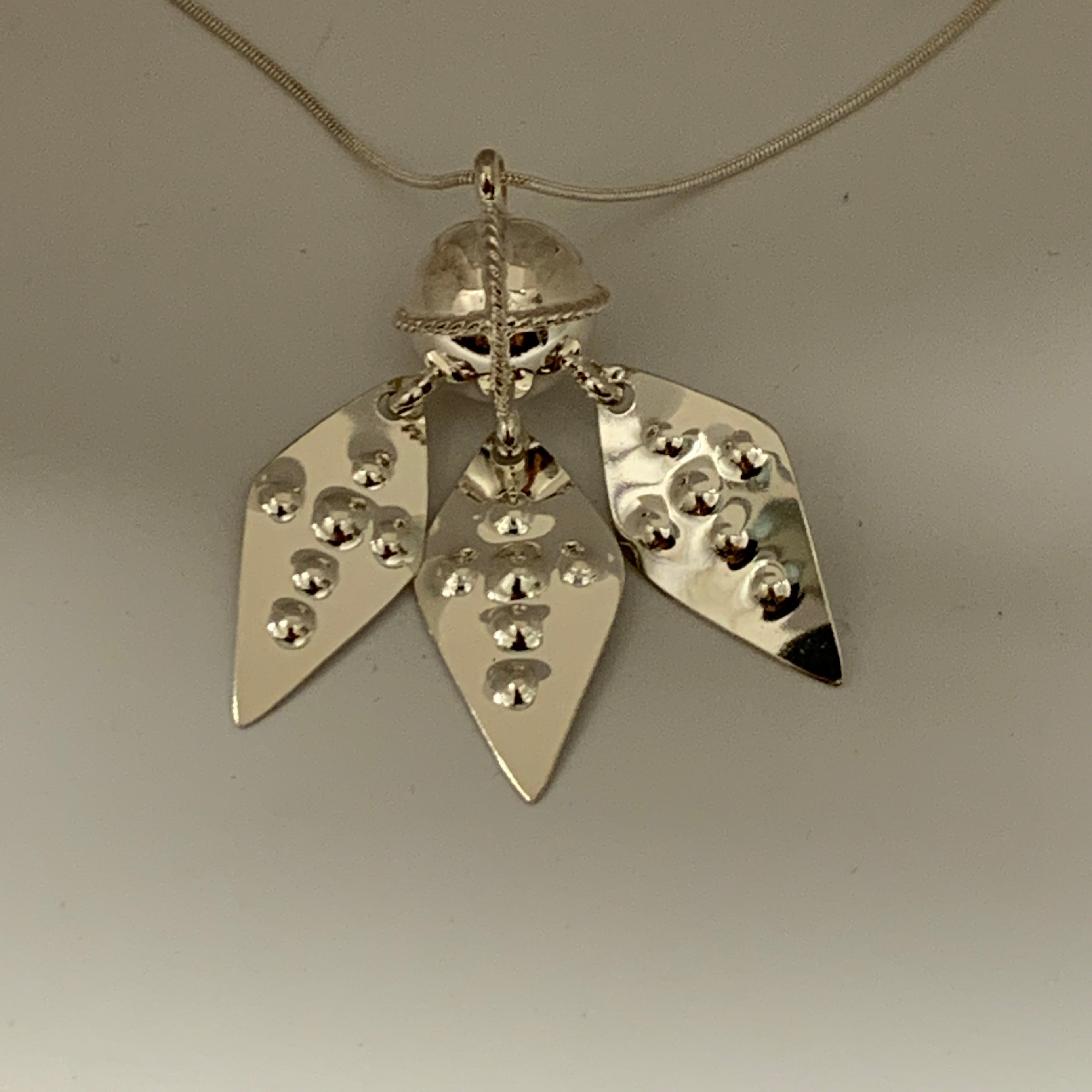 Vacker samisk komsekula i silver med tre silverlö som halsband. I förlaga från Raukasjö, Jämtland. Kulans diameter är 14 mm.Levereras med silverkedja som är 50 cm lång. Komsekulan är ett gammalt samiskt kultursmycke. Finns hos Risfjells Sameslöjd, Vilhelmina i södra Lappland.