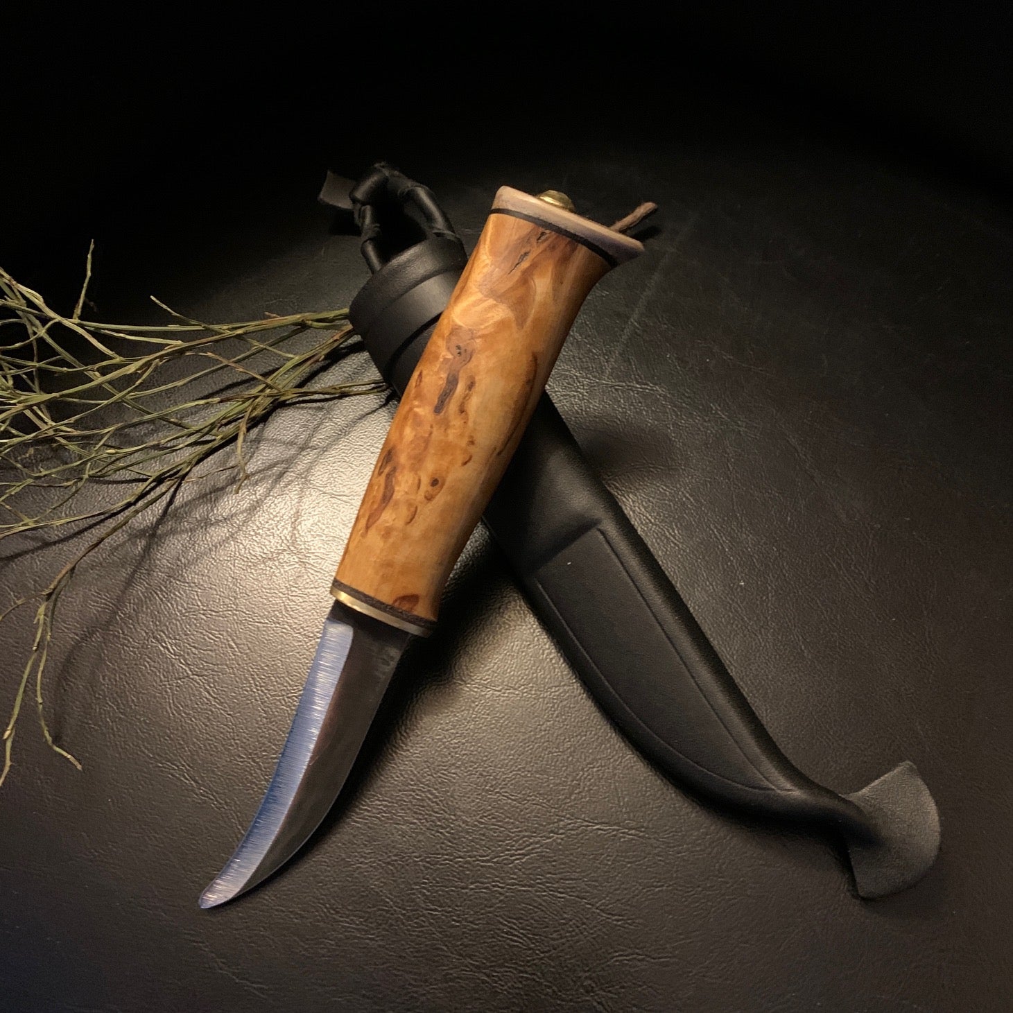 Jaktkniv buköppnare i masurbjörk och horn med böjt blad i kolstål. Bladets längd är 88 mm. Knivens längd är 18 cm. Knivens hela längd i fodral är 22 cm. Finns hos Risfjells Sameslöjd i Vilhelmina.