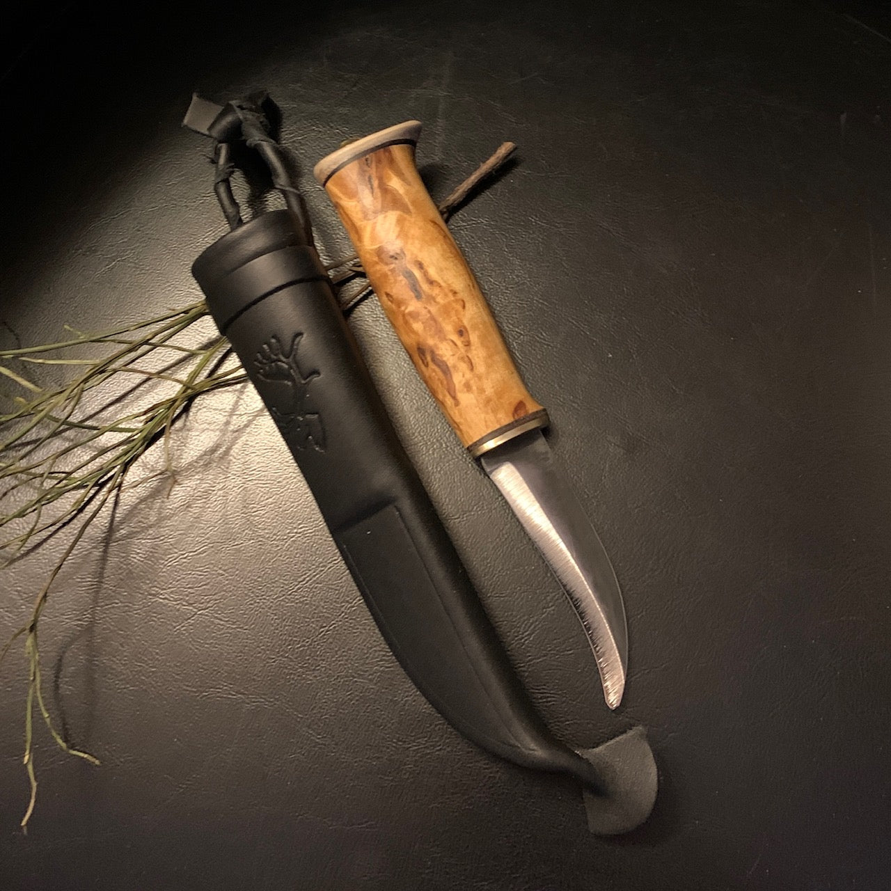 Jaktkniv buköppnare i masurbjörk och horn med böjt blad i kolstål. Bladets längd är 88 mm. Knivens längd är 18 cm. Knivens hela längd i fodral är 22 cm. Finns hos Risfjells Sameslöjd i Vilhelmina.