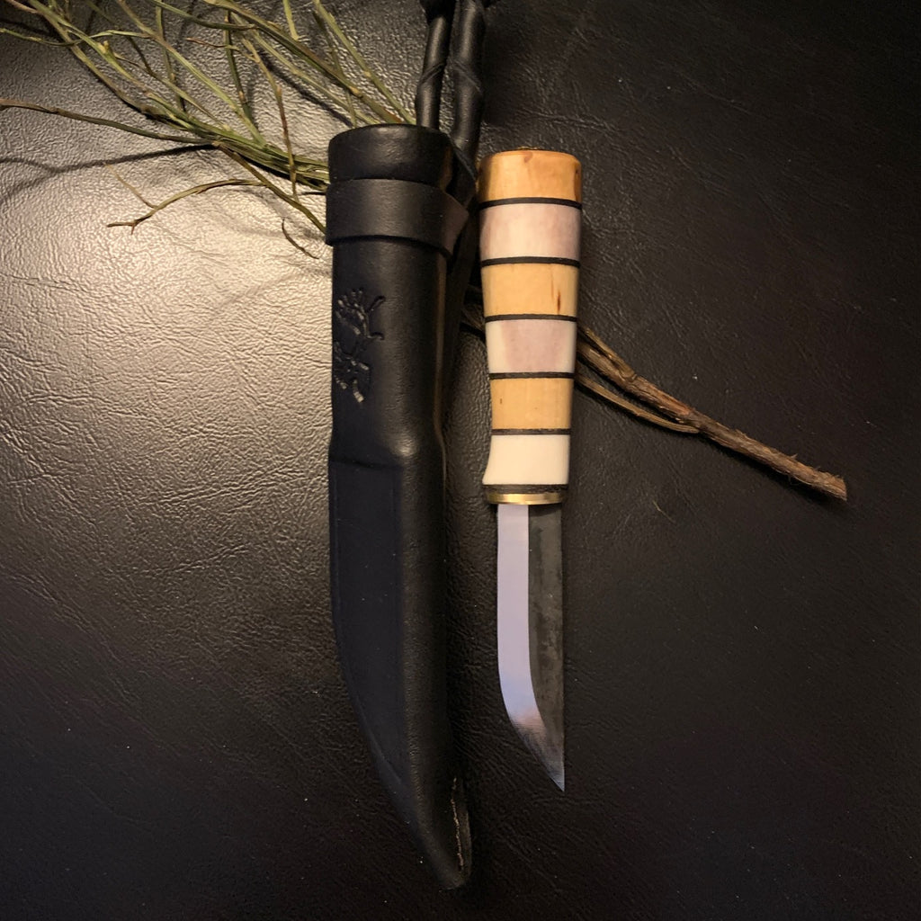 Liten kniv i björk och horn i storlek av kalvmärkarkniv. Knivens längd är12,5 cm lång varav bladet är 55 mm långt och 13 mm brett. Knivbladet är i kolstål. Knivens längd instppad i fodralet är 16,7 cm. Finns hos Risjfells Sameslöjd i Vilhelmina södra Lappland.