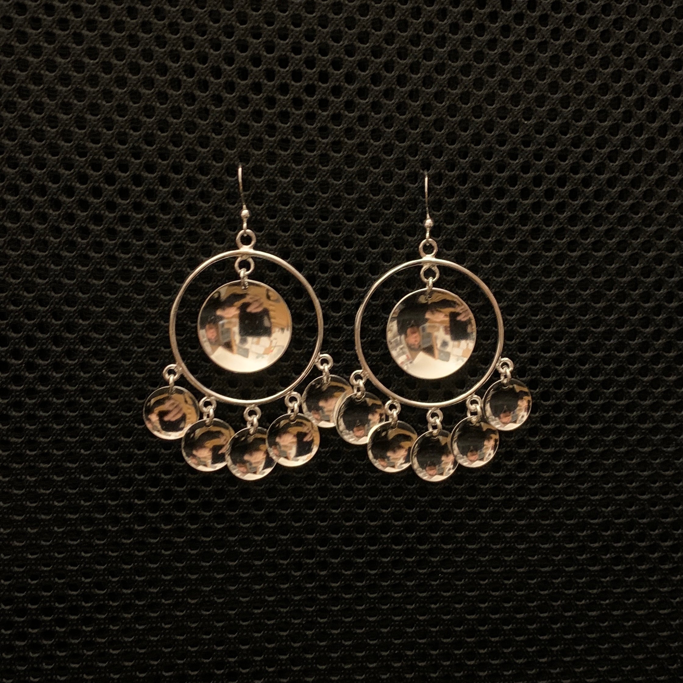 Örhängen Solglitter samisk design i silver stor modell. Diameter 32 mm. Längd 50 mm plus krok. Fem små konkava hängen i nedre kant och ett stort konkavt hänge i mitten. Finns hos Risfjells Sameslöjd, Vilhelmina