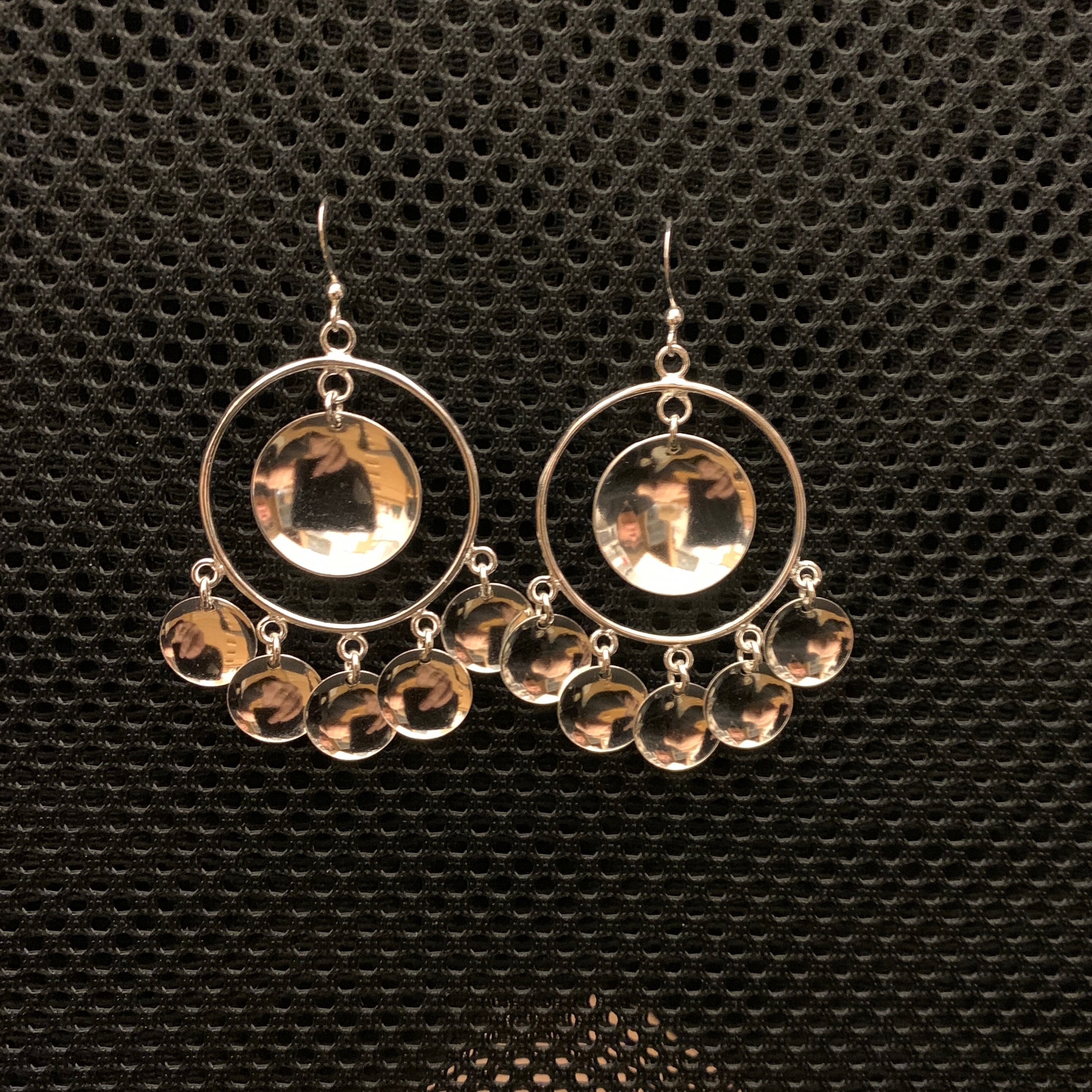 Örhängen Solglitter samisk design i silver stor modell. Diameter 32 mm. Längd 50 mm plus krok. Fem små konkava hängen i nedre kant av den stora ringen och ett stort konkavt hänge i mitten av ringen. Finns hos Risfjells Sameslöjd, Vilhelmina