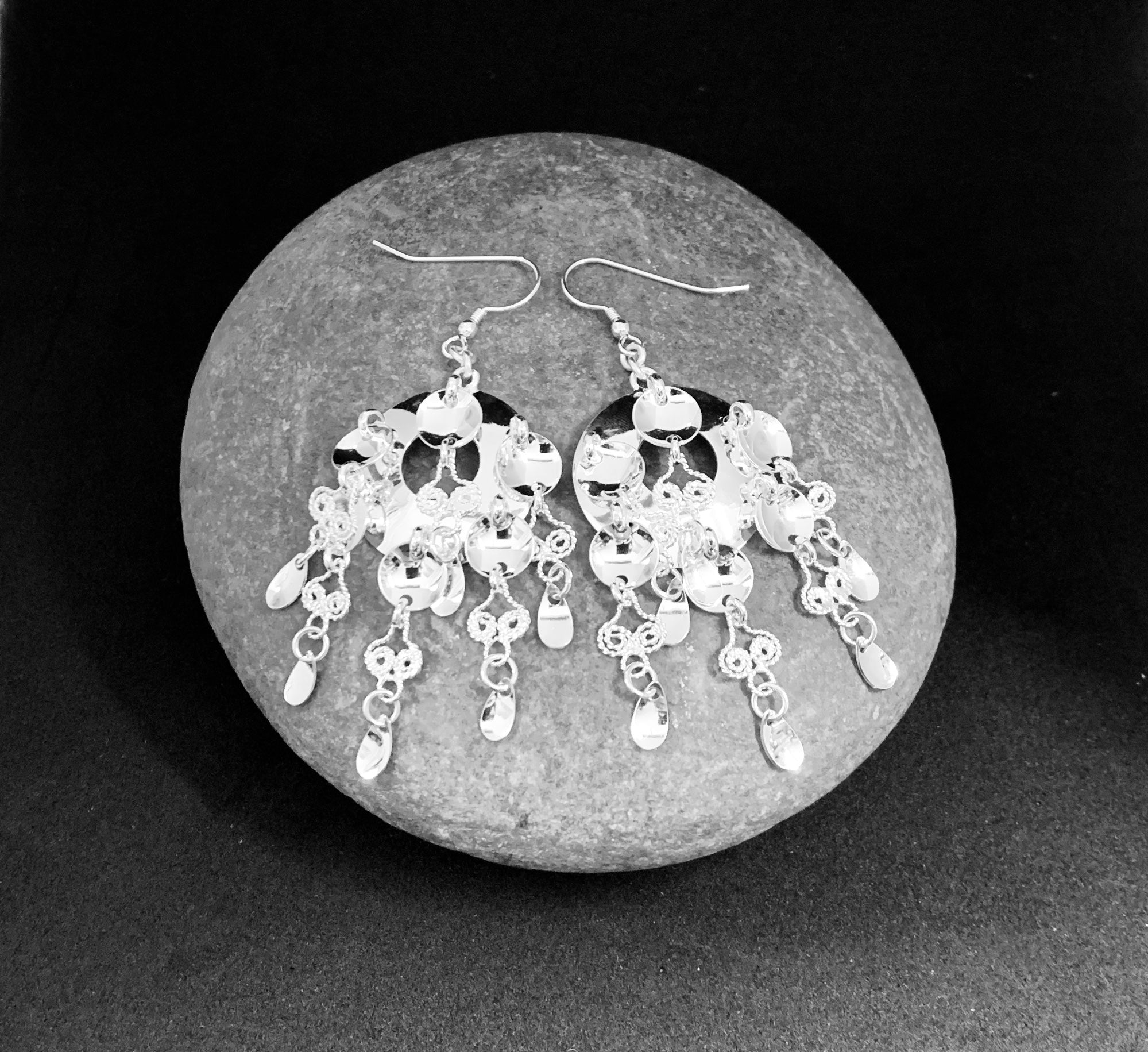 Örhängen i silver med rik samisk utsmyckning med löv, runda skålar och Filigranarbete. Längd från krokens övre del till nedersta lövet är 75 mm, bredd 25 mm. Örhänget är inspirerat av Sven-Åke Risfjells farmor Sara Alvina Sofia Sjulsdotters brosch. 