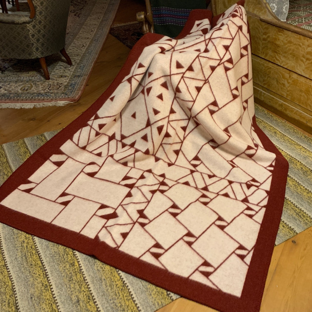 Pläd i ull. En unikt designad pläd av sameslöjdarna Doris och Sven-Åke Risfjell Vilhelmina Risfjells sameslöjd. Det gamla Nåjdmönstret från Marsfjäll återbördat i slöjden igen av Sven-Åke Risfjell och i textil produktion av Doris Risfjell. Här i vinröd-vit färgställning.