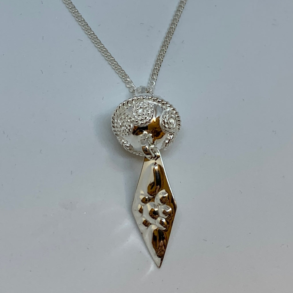 Komsekula i silver med midja, filigrandekor och punsat hängande löv. Kulan är 12 mm i diameter. Det hängande punsade lövets längd är 20 mm. Silverkedja 45 cm medföljer. Komsekulan är ett samiskt kultursmycke.Finns hos oss Risjfells Sameslöjd i Vilhelmina, södra Lappland.