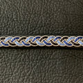 Tenntrådsarmband Midvinternatt  med flätning av tenntråd samt svart och blått tvinnat garn på svart renskinn. Knapp i renhorn och ögla i tvinnat renskinn. Bredd ca 10 mm. Samiskt hantverk av Doris Risfjell, Risfjells Sameslöjd i Vilhelmina.